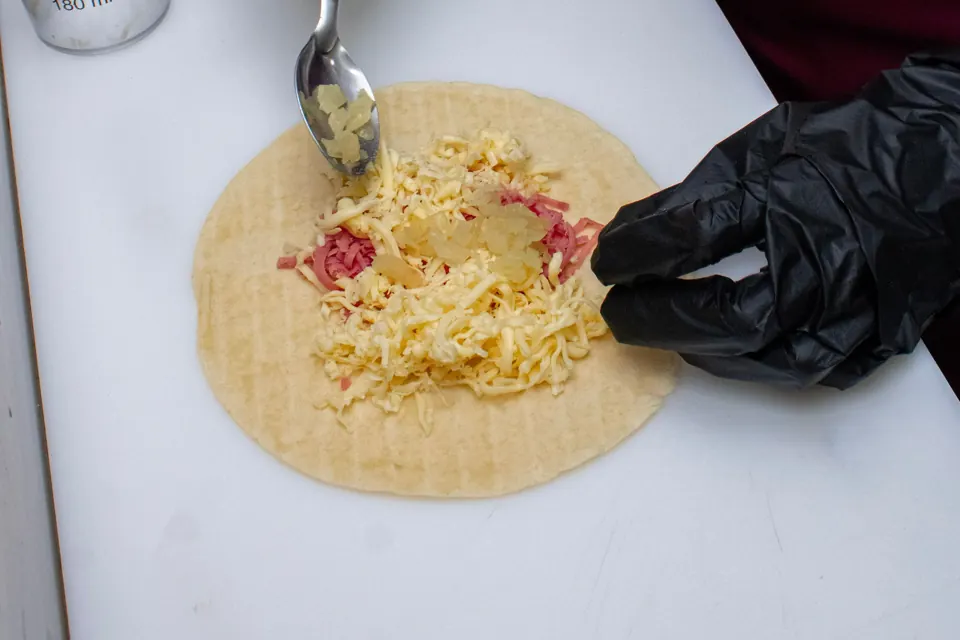Manos con guantes preparando alimentos en una cocina.